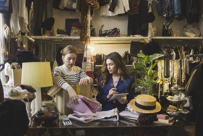 Multi-ethnic female colleagues packing product in box at clothing store