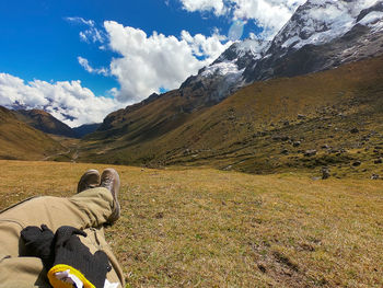 Man sitting on mountain against sky