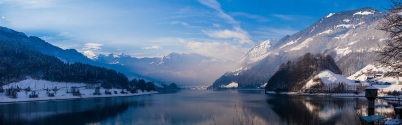 Scenic view of lake by snowcapped mountains against sky