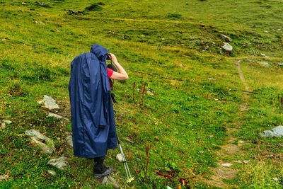 Side view of woman looking through binoculars while standing on land