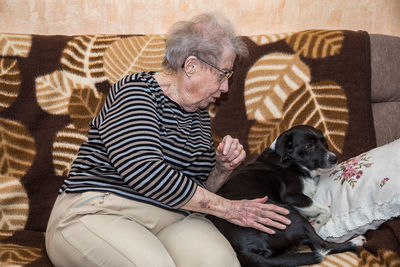 Midsection of man with dog sitting at home