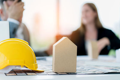 Architects working at desk with hardhat and model home in foreground at office