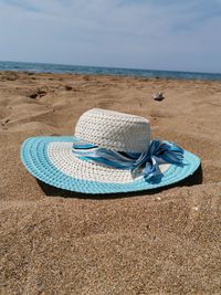 Close-up of shoes on sand at beach against sky