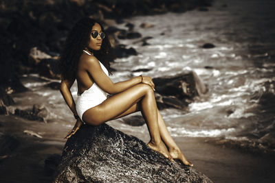 Midsection of woman on rock by sea