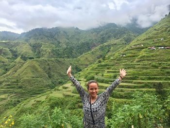 Portrait of a smiling young woman standing on landscape