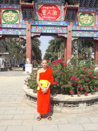 Portrait of woman standing against red wall