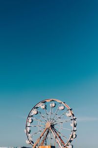 Low angle view of ferris wheel against clear blue sky