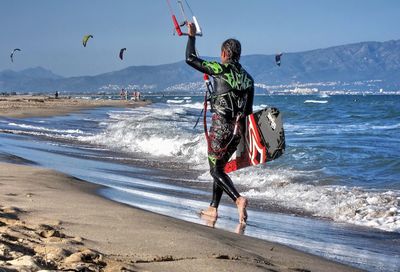 Full length of man jumping on beach against sky