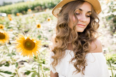 A young girl with a model appearance, in denim trousers and a white blouse in a sunflower field