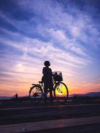 Silhouette of motorcycle against cloudy sky at sunset