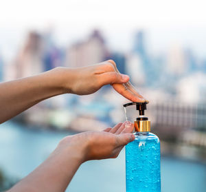 Close-up of hand holding bottle against blurred background