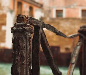 Close-up of rusty metal fence against old building