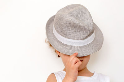 Boys covering face with hat against white background