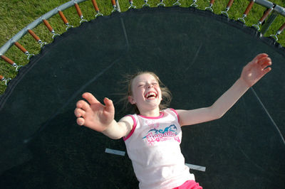 Happy girl lying on trampoline outdoors