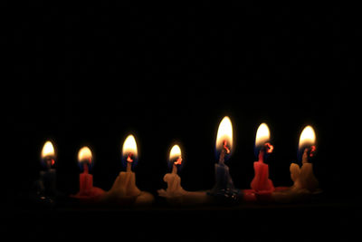 Close-up of illuminated candles against black background