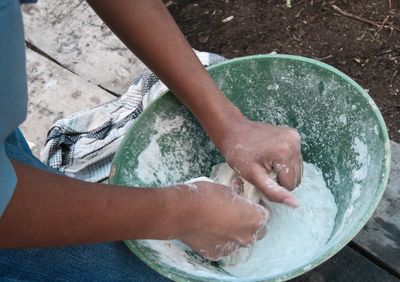 Midsection of person kneading dough while sitting on bench