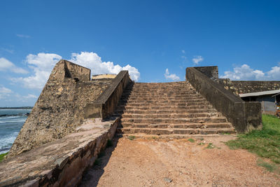 Old building by sea against blue sky