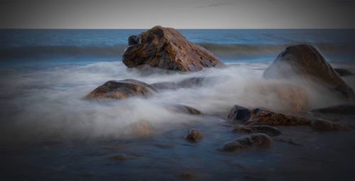 Scenic view of rocks in sea against sky