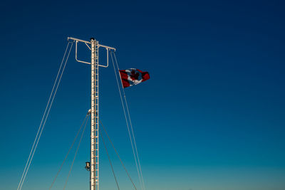 Low angle view of flag against clear blue sky