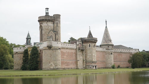 View of building by lake against sky