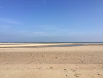 Scenic view of beach against blue sky