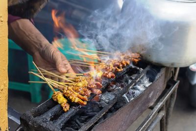 Midsection of man preparing food on barbecue grill