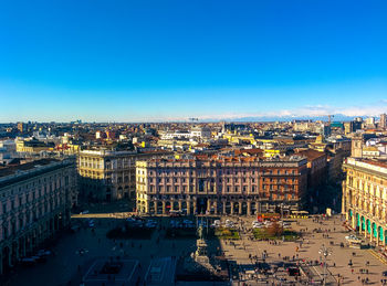 High angle view of city buildings against blue sky