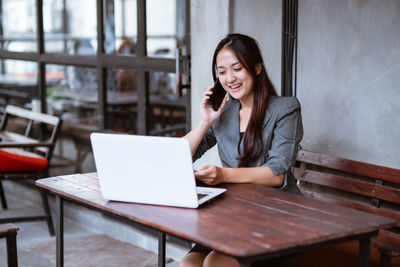 Portrait of young woman using laptop at table