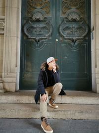 Full length of man looking away while sitting outside building