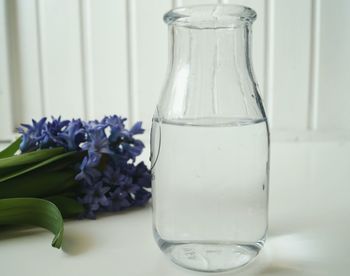 Close-up of water in bottle by hyacinths on table at home