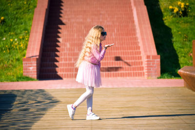 Full length of young woman walking on boardwalk