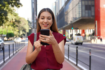 Attractive business woman watching her phone on paulista avenue in sao paulo, brazil