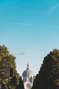 Low angle view of trees and buildings against blue sky