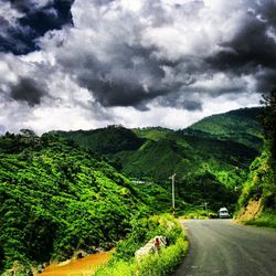 Country road against cloudy sky