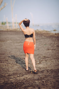 Full length rear view of woman standing on beach