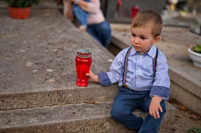 Little toddler holding a candle on the grave