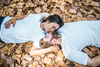 Couple kissing while relaxing on autumn leaves
