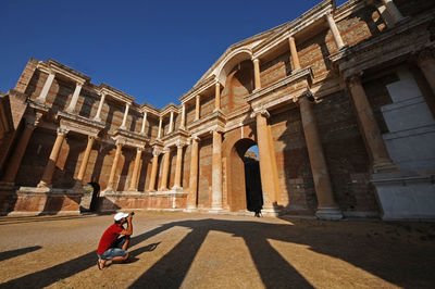 Man photographing of historical building against sky