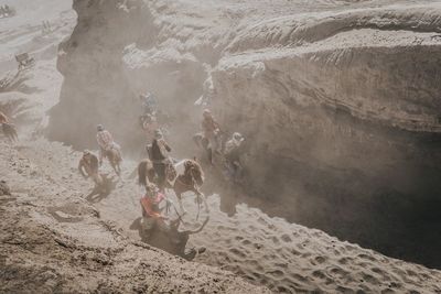 A group of people riding a horse to travel up the volcano  in the midst of the dust.