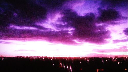 Scenic view of illuminated city against cloudy sky