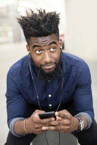 Man listening to music from mobile phone while looking away in city