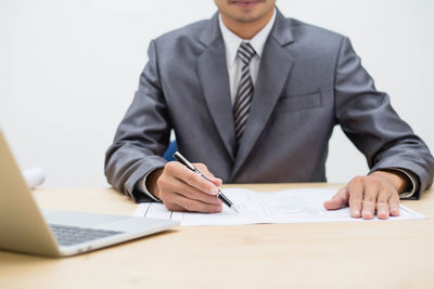 Midsection of businessman analyzing while sitting at office