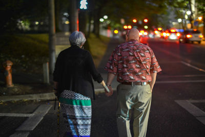 Rear view of people walking on street in city