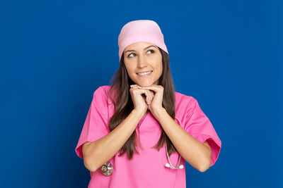 Portrait of a smiling young woman against blue background