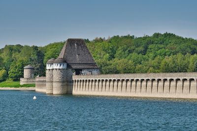 Built structure by river against sky