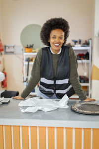 Portrait of smiling female worker leaning on counter at recycling center