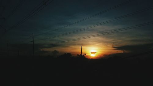 Silhouette electricity pylon against sky during sunset