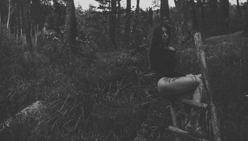 Portrait of woman sitting on land in forest