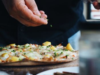 Close-up of hand holding pizza