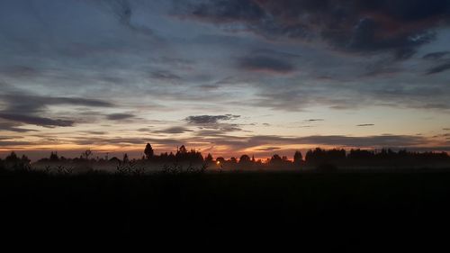 Silhouette landscape against dramatic sky during sunset